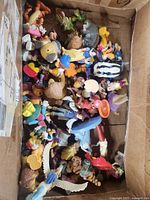 Box with multiple vintage Disney toy figures piled together showing a variety of characters and colors.