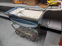 Full side view of the vintage baby buggy stroller showing metal frame, wheels, and fabric details.