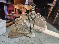 Front view of the vintage cast iron peacock fireplace grate displaying fan tail spread open and side surroundings.