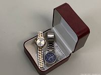 Two-tone Wittnauer watch alongside men's Timex chronograph watch inside red partial original box
