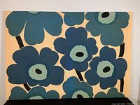 Full view of the stretched fabric showing the iconic Unikko pattern in blue and turquoise on beige background.