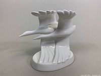Front and side angle of white porcelain Royal Doulton 'Going Home' figurine showing two birds in flight on an oval base.