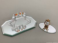 Wide view of both crystal figurines on mirror bases showing full shapes and colors.