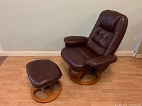 Full view of vintage leather reclining lounge chair and matching ottoman, showing dark brown leather upholstery and circular wooden bases.