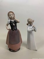 Two LLADRO and NAO by LLADRO porcelain figurines displayed side by side on a neutral background.