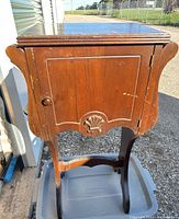 Full view of antique wooden chamber pot cabinet with towel rods on sides, showing overall shape, door, and carved detail.