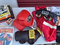 Overview of the boxing gloves, headgear, books, and magazines laid out on a table