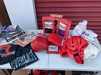 Overview of the boxing equipment and collectibles on table including gloves, boots, clothing, and books.