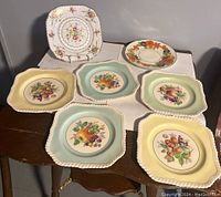 Image showing five Johnson Brothers fruit plates with fruit designs and colored backgrounds in yellow and blue, plus one Royal Albert and one Grindley plate.