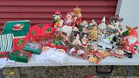 Wide view of multiple Christmas decorations, towels, ornaments, stocking hooks displayed on a white table