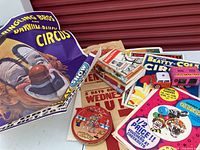 Overview of most items including folded Ringling Bros. circus poster, several smaller circus posters, circus books stacked, small metal circus animal truck toy, and round circus cookie tin.