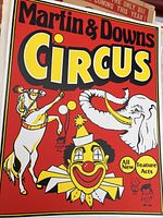 Close-up photo of Martin & Downs Circus poster with bright red background and illustrations of clown, horse, and elephant