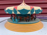 Plastic circus merry-go-round toy with red and yellow striped top and molded animal and carriage figures on base