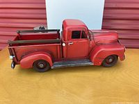 Side view showing red metal pickup truck with open cargo bed and detailed tires, side mirrors, and step rails