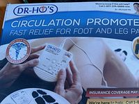 Box top showing product branding, a person holding the control unit, and marketing text about fast relief for foot and leg pain.
