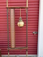 Full assembly showing tension-fit poles, two wood shelves, white lattice panel and hanging globe lamp