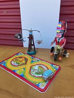 Photo showing all items: cycling monkey on tricycle, rotating airplane ride, blue VW van on colorful racetrack base