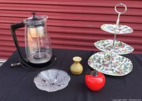 Five vintage entertaining items on black cloth with red garage door background.