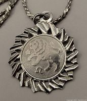 Close-up photo of sterling silver Leo zodiac sunburst pendant showing detailed engraving and silver markings.
