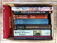 Top-view of nine art and history books stacked in a box showing titles and varying colors of covers and bindings