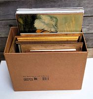 Box containing multiple framed paintings, prints and artworks of various sizes in protective cardboard.