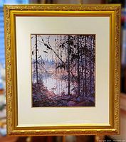 Full view of large gold ornate framed art print depicting a forest scene by a river with tall pine trees and branches in foreground, showing overall condition and framing.