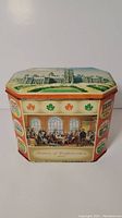 Front side showing Fathers of Confederation scene and maple leaf motifs on the biscuit tin