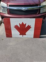 Front view of wooden artwork showing hand-painted Canadian flag in red and white.