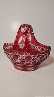 Front and overall view of cranberry red cut crystal candy basket with handle and intricate cut designs.