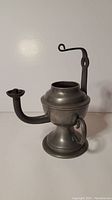 Front and side view of the small Dutch pewter oil lamp with spout, rounded base, carrying handle, and wall mounting bracket loop.