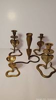 All five brass snake-shaped holders arranged in a row against white background