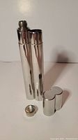 Open view of the stainless steel dual container showing flask side with screw top cap removed and the cigar holder section open