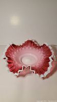 Top view of a freeblown cranberry and milk glass bowl showing the ruffled edge and coloring.