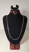 Full view of the sterling silver flat serpentine necklace displayed on a black mannequin, showing length and shape.