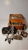 Photo of beaded Louis Vuitton style purse layered with multiple bracelets and necklaces, displayed on wooden box