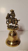 Full view of the brass bell showing the Paul Revere figure on horseback and the bell body.