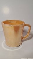 Front side view of satin peach Fire King coffee mug showing overall shape and color
