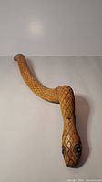 Full length view of hand carved wooden snake showing the curved body and scale detail