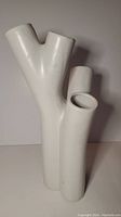 Full view of the white tubular ceramic vase showing its three branches with open tops and glossy finish