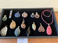 Full view of 14 gemstone pendants on black tray.