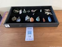Tray holding 15 gemstone pendants, assorted shapes and colors, showing full lot.