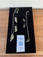 Two new sterling silver necklace and earring sets displayed on black velvet board. Includes cluster bead design set and twisted shape design set.