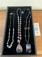 Full view of all three handcrafted necklaces laid out on a black tray showing stone beads and pendants.