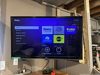 Front view of the powered on LG TV showing the Roku menu screen.