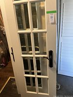 Front view of a white French door with multiple beveled glass panes and metal handle, showing the door's overall condition and style.