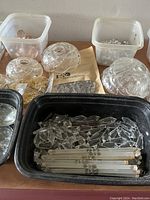 Plastic tubs filled with various chandelier crystal pieces including long rectangular prisms and circular covers.