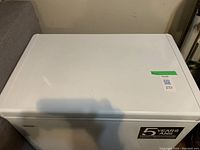 Closed top view of the white chest freezer showing brand label and warranty sticker.