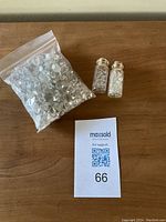 Photo showing a large resealable plastic bag filled with clear Herkimer diamond quartz crystals and two small glass vials filled with similar smaller crystals, all placed on a wooden surface next to a collection lot card.