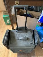 Closed jewellery case showing telescopic handle extended and wheels at base