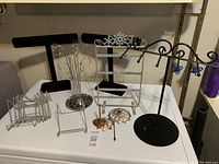 Photo showing the full set of jewellery display items including black velvet T-bar stand, metal multi-tiered stand, silver earring stands, copper leaf candle holders, and metal grid stands.